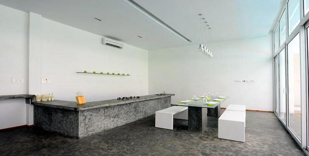 The bar counter is also made of epoxy and concrete and is accompanied by smart white bar stools. The wall here flaunts a savvy metal plank with nails that double up making up for bottle holders.
