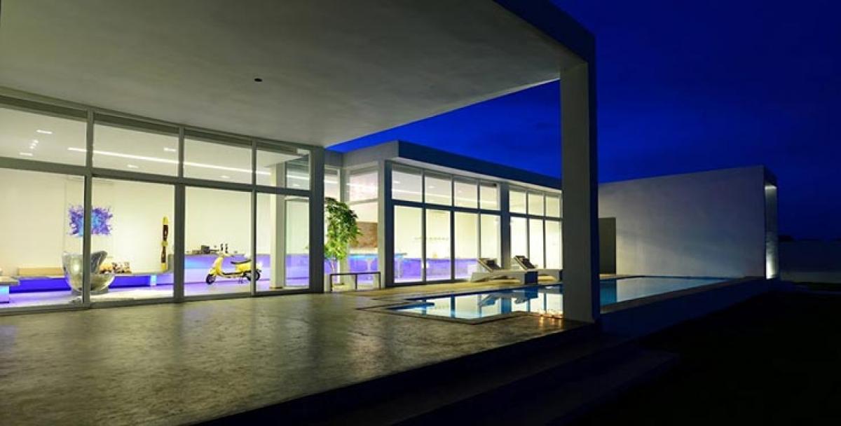 The long dining table has an elegant glass table top which is complement with white benches. The dining space overlooks the pool and the deck.