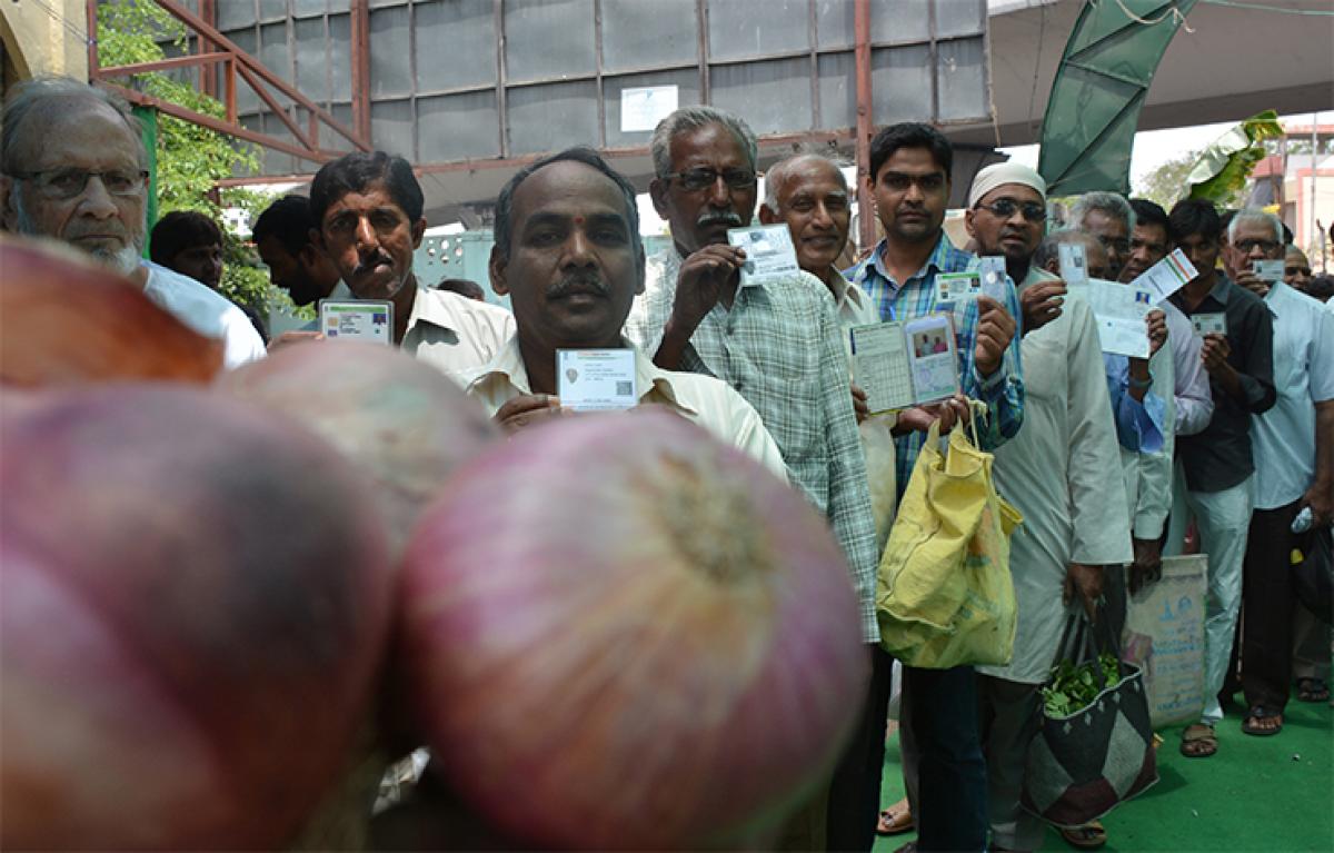 People standing in a queue with their identity cards to purchase onions at the subsidy sales counter at Mehdipatnam Rythu Bazaar in Hyderabad on Wednesday 