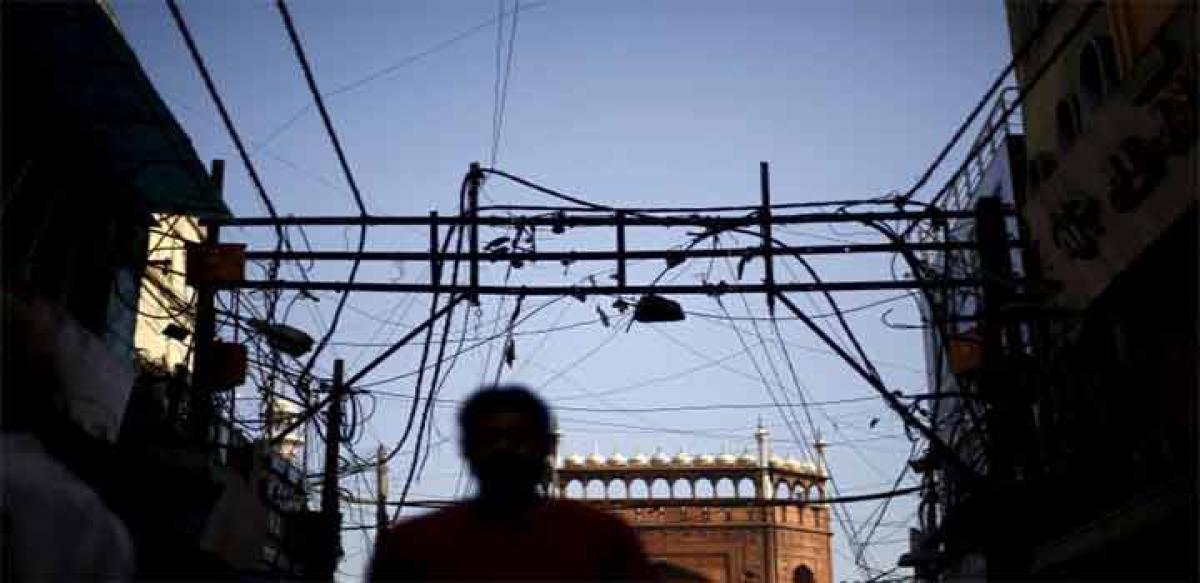 A man is silhouetted against the backdrop of Jama Masjid (Grand Mosque) as overhead power cables are seen in the old quarters of Delhi