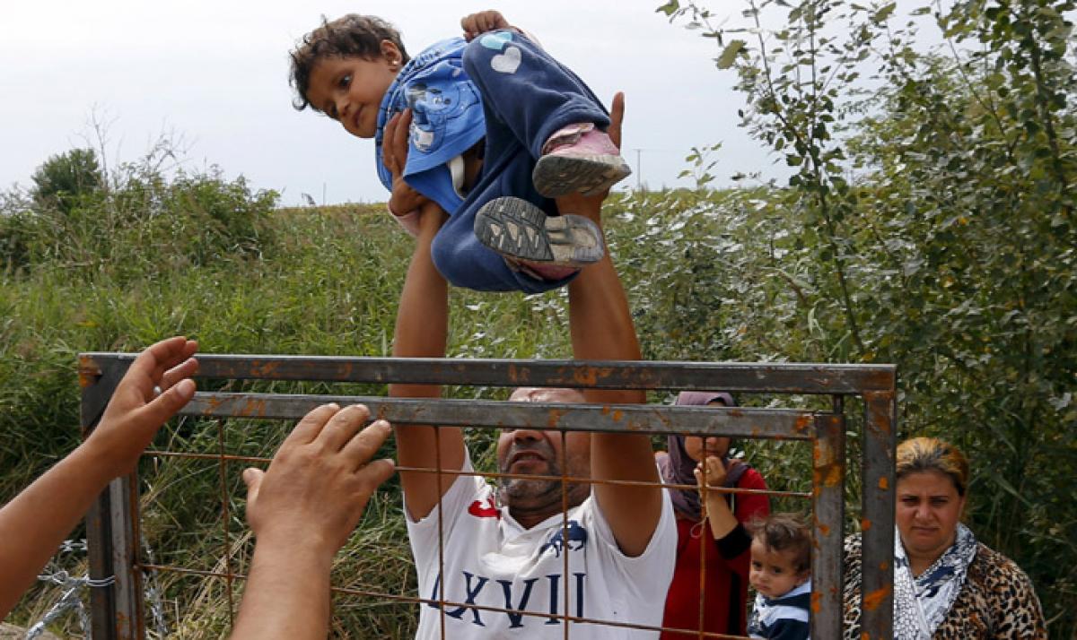 A Syrian migrant lifts a child over a fence on the Hungarian-Serbian border near Asotthalom in Hungary. (Reuters)