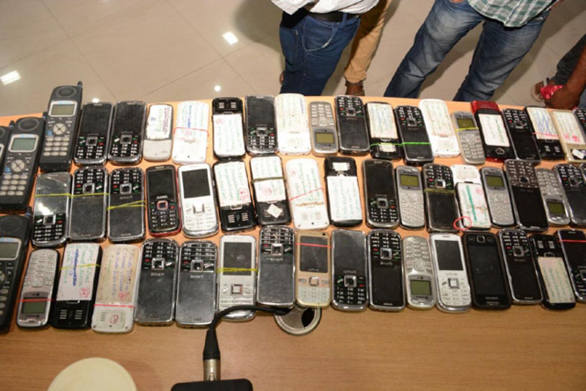 A gang member (covering his face) arrested for creating scores of fake PAN cards, voter IDs and credit cards in Hyderabad on Tuesday. (Inset) Mobile phones and PAN cards recovered from them.