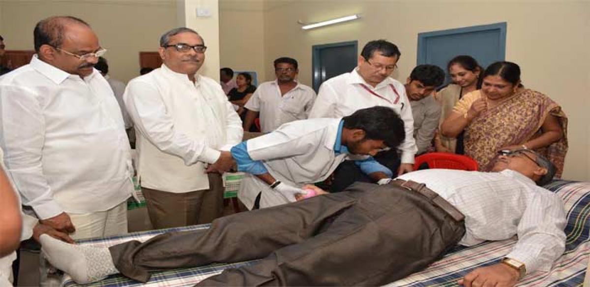 A donor undergoing blood donation at the camp flanked by ONGC officials