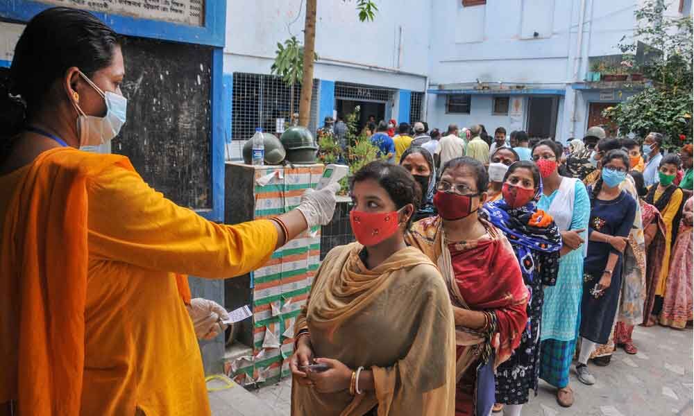 Voters undergo thermal screening as they stand in a queue to cast their votes at a polling station during the third phase of West Bengal Assembly elections. (L) BJP leader E Sreedharan and his wife Radha Sreedharan