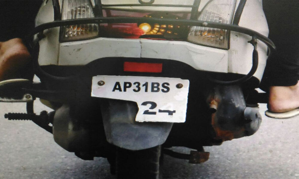 A motorist riding a two-wheeler with a broken registration number plate